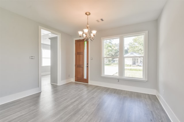 unfurnished room featuring wood-type flooring and an inviting chandelier