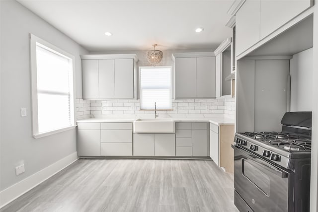 kitchen with light wood-type flooring, plenty of natural light, sink, and gas stove