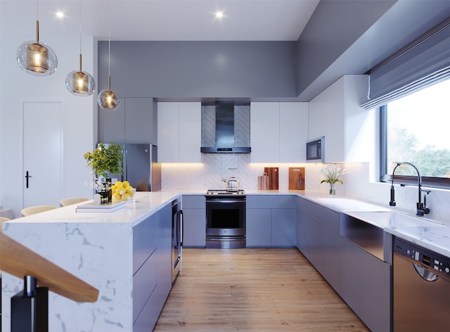 kitchen with decorative light fixtures, backsplash, stainless steel appliances, a center island, and wall chimney exhaust hood