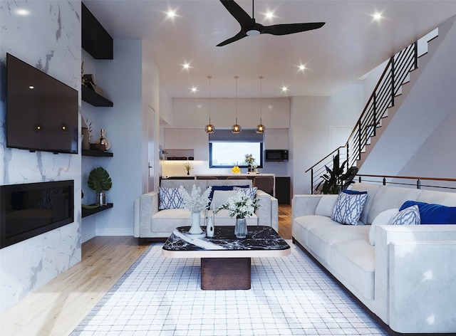 living room featuring ceiling fan, a towering ceiling, and light hardwood / wood-style flooring