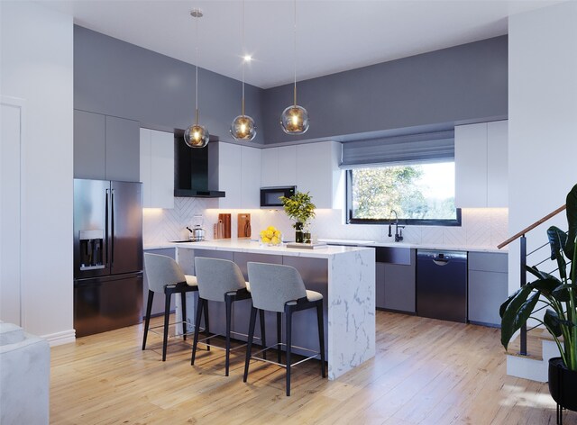 kitchen with hanging light fixtures, tasteful backsplash, wall chimney range hood, a breakfast bar area, and black appliances