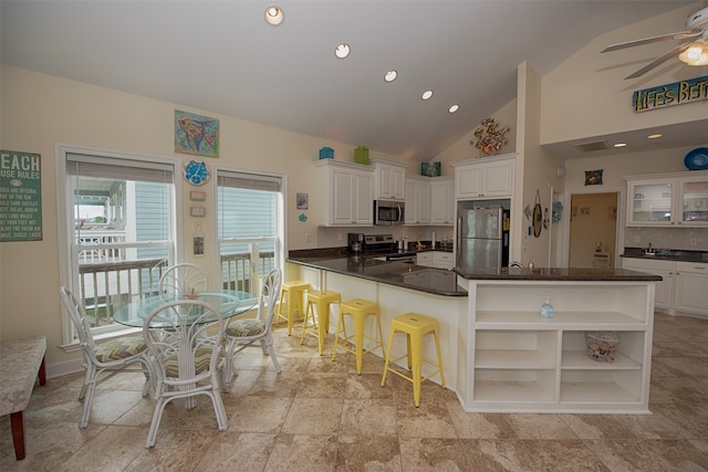 kitchen featuring kitchen peninsula, appliances with stainless steel finishes, ceiling fan, light tile flooring, and white cabinets