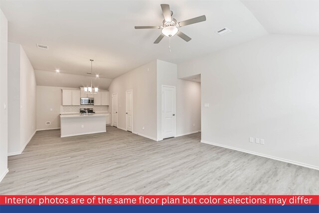 unfurnished living room featuring ceiling fan with notable chandelier, vaulted ceiling, and light hardwood / wood-style flooring