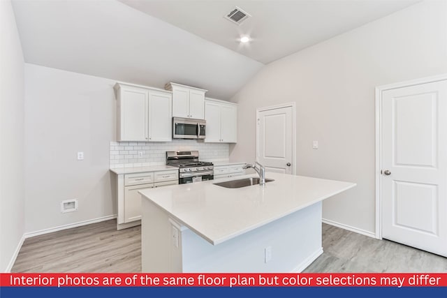 kitchen with an island with sink, stainless steel appliances, white cabinetry, lofted ceiling, and sink