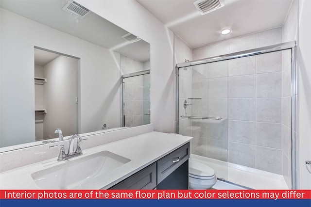 bathroom featuring toilet, an enclosed shower, and vanity