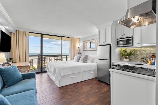 bedroom featuring stainless steel fridge, a water view, access to outside, crown molding, and dark hardwood / wood-style flooring