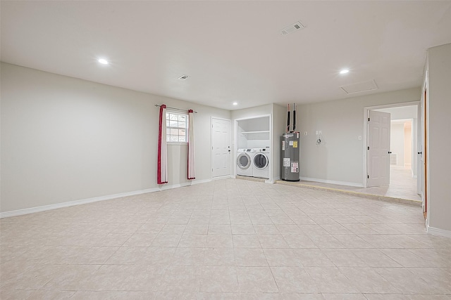 washroom featuring water heater, washing machine and clothes dryer, and light tile patterned floors