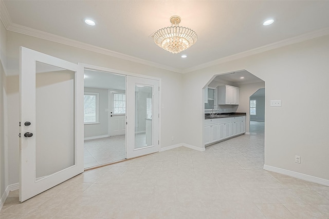 interior space with sink, light tile patterned flooring, an inviting chandelier, and ornamental molding