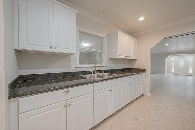 kitchen featuring crown molding, light tile patterned floors, dark stone counters, sink, and white cabinetry