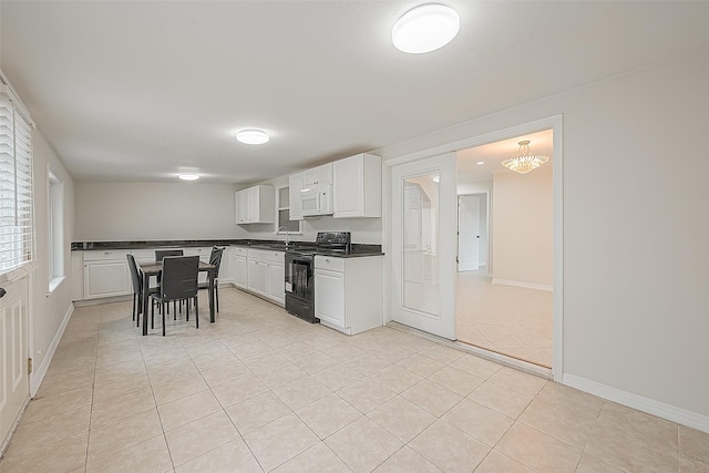 kitchen with white cabinets, light tile patterned flooring, black range with electric stovetop, and a chandelier