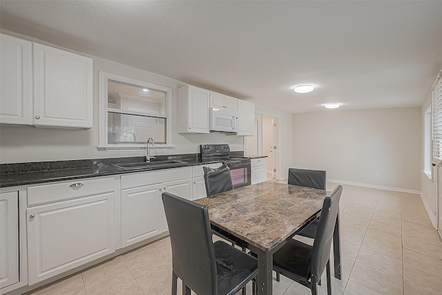 kitchen with sink, white cabinets, light tile patterned floors, and black electric range oven