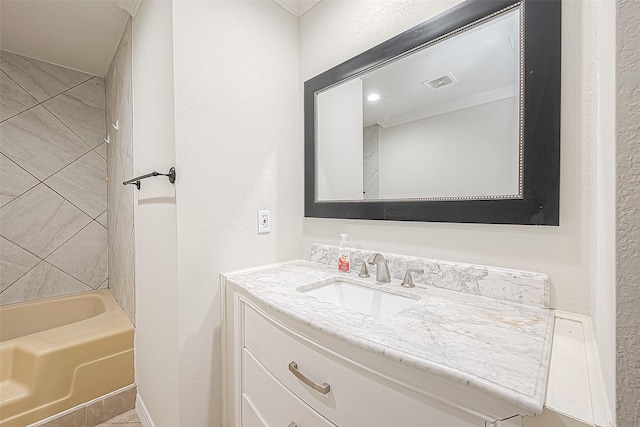 bathroom featuring tiled shower / bath, crown molding, and vanity