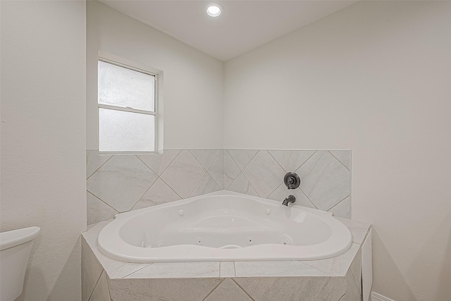 bathroom featuring a relaxing tiled tub and toilet