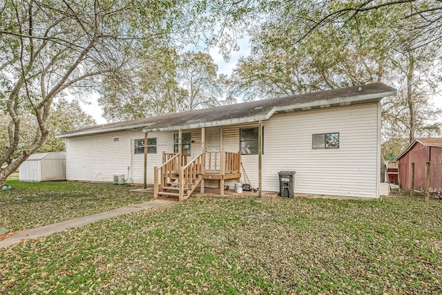 rear view of property featuring a storage unit and a lawn