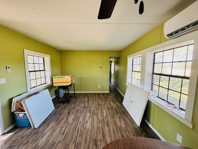 interior space with ceiling fan, a wall mounted air conditioner, and dark hardwood / wood-style floors