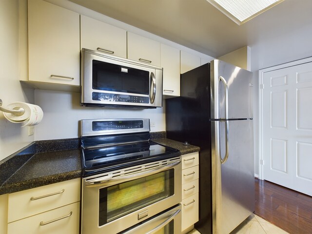 kitchen featuring dark stone countertops, appliances with stainless steel finishes, and light wood-type flooring