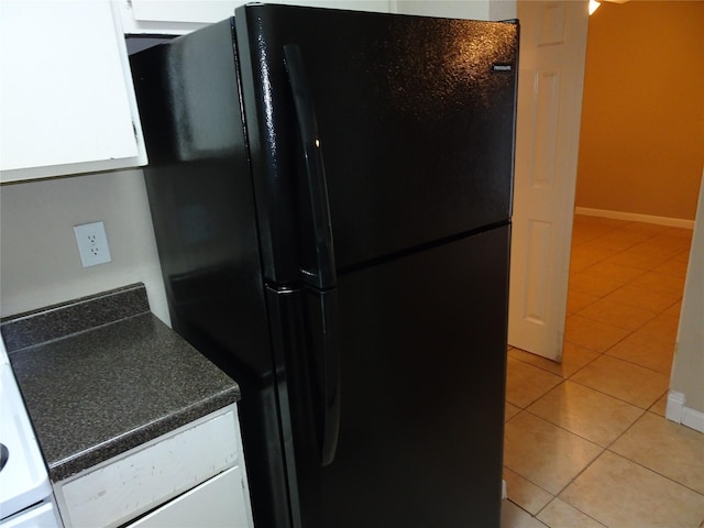 kitchen with white cabinets, black fridge, and light tile patterned floors