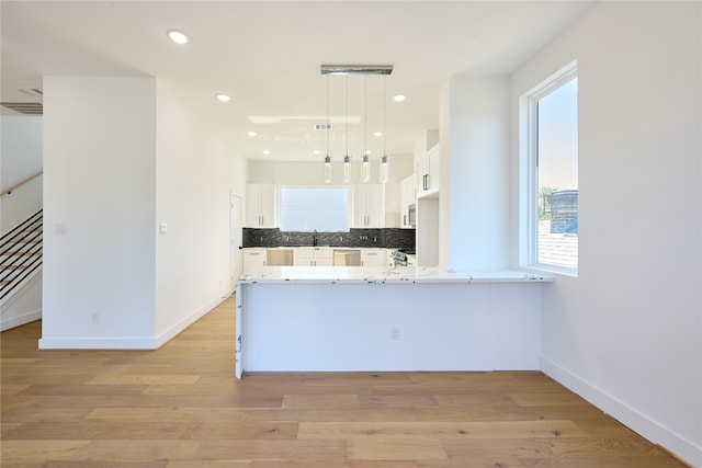 kitchen featuring light hardwood / wood-style floors, pendant lighting, decorative backsplash, kitchen peninsula, and white cabinets