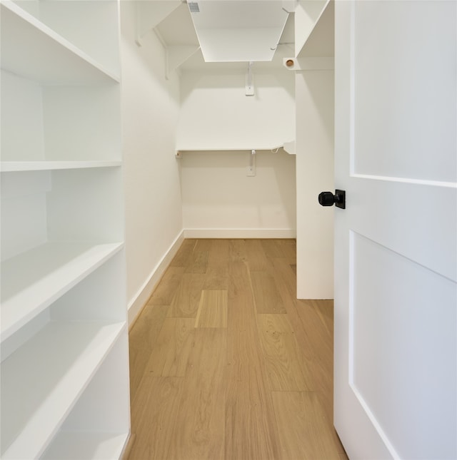 walk in closet with light hardwood / wood-style flooring