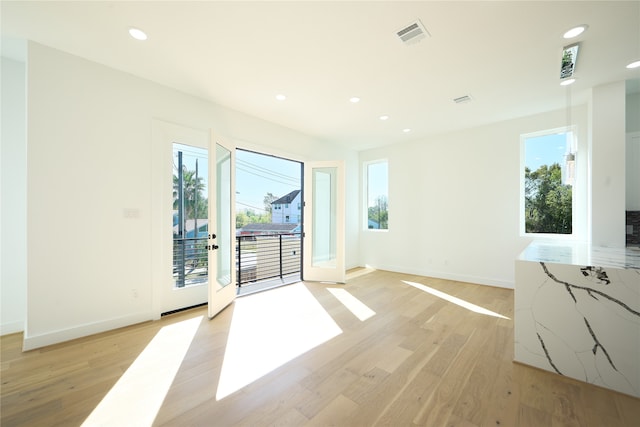 spare room featuring plenty of natural light, light hardwood / wood-style floors, and french doors