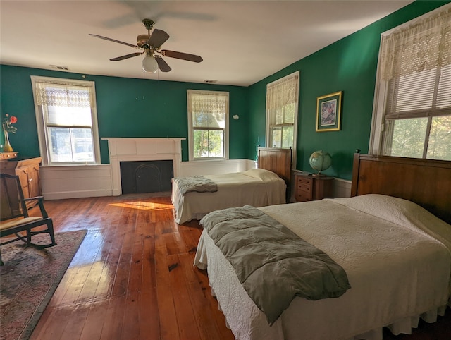 bedroom featuring ceiling fan, hardwood / wood-style flooring, and multiple windows