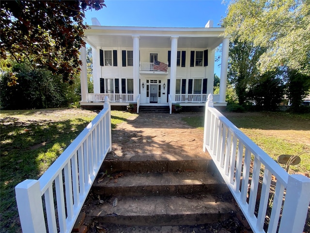 back of house featuring a balcony, a yard, and a porch