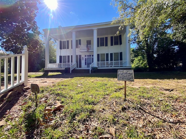 view of front facade with a balcony and a front lawn