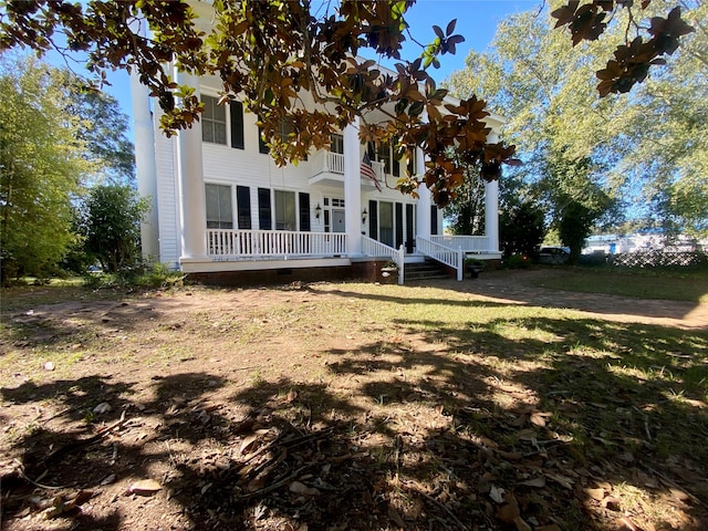 back of house with a yard and a balcony