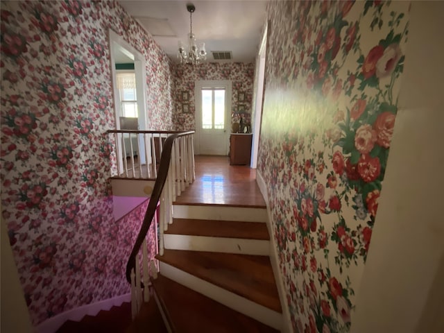 stairway featuring a notable chandelier