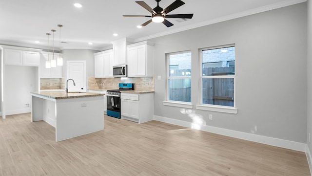 kitchen with stainless steel appliances, a center island with sink, light hardwood / wood-style flooring, white cabinetry, and hanging light fixtures