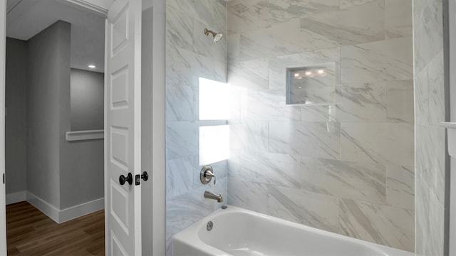 bathroom featuring wood-type flooring and tiled shower / bath