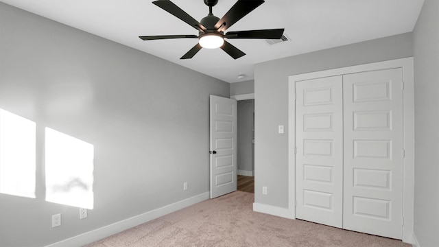 unfurnished bedroom with ceiling fan, light carpet, and a closet