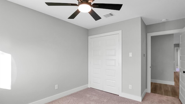 unfurnished bedroom featuring ceiling fan, light colored carpet, and a closet