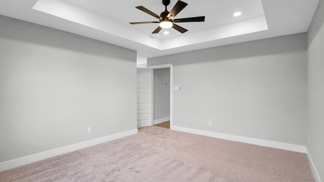 carpeted empty room featuring a raised ceiling and ceiling fan