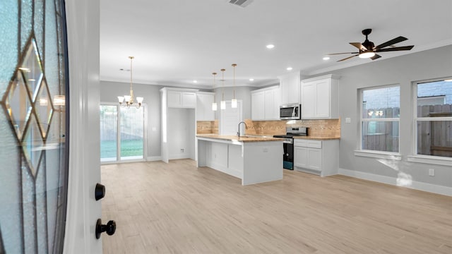 kitchen with white cabinets, pendant lighting, light wood-type flooring, and appliances with stainless steel finishes