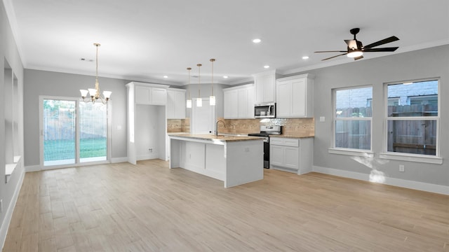 kitchen featuring white cabinets, stainless steel appliances, decorative light fixtures, and light hardwood / wood-style floors