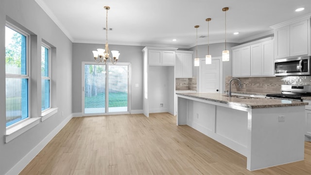 kitchen with decorative light fixtures, sink, appliances with stainless steel finishes, and an island with sink