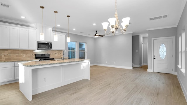 kitchen with ceiling fan with notable chandelier, gas stove, light hardwood / wood-style floors, white cabinetry, and an island with sink