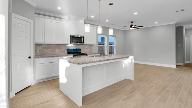 kitchen featuring white cabinetry, black range oven, light hardwood / wood-style floors, a center island with sink, and ornamental molding