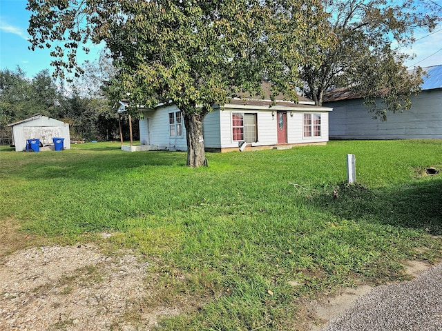 view of front of home with a front yard and a storage shed