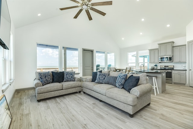 living room featuring high vaulted ceiling, light hardwood / wood-style floors, and ceiling fan