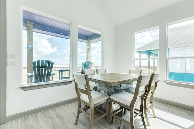 dining space with vaulted ceiling, light wood-type flooring, and a wealth of natural light