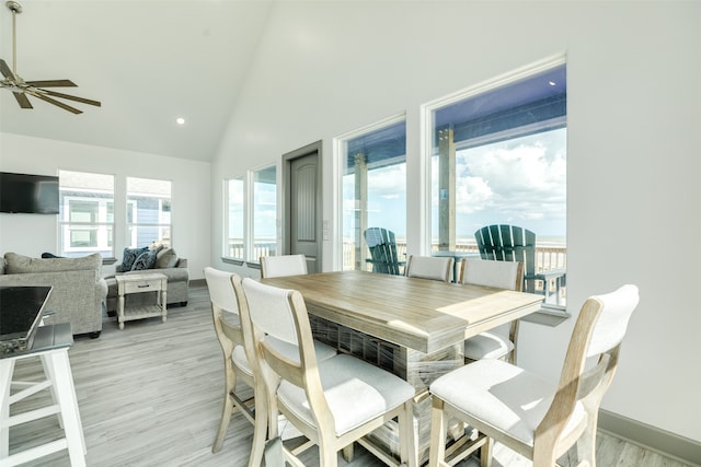 dining space with high vaulted ceiling, light hardwood / wood-style floors, and ceiling fan