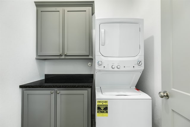 washroom featuring cabinets and stacked washing maching and dryer