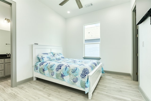 bedroom featuring ensuite bath, light hardwood / wood-style flooring, ceiling fan, and sink