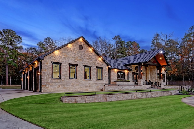 back house at dusk featuring a lawn