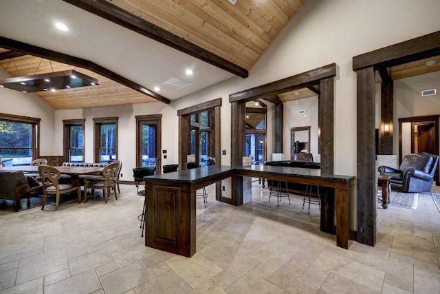 interior space with a breakfast bar, dark brown cabinets, wooden ceiling, a kitchen island, and beamed ceiling