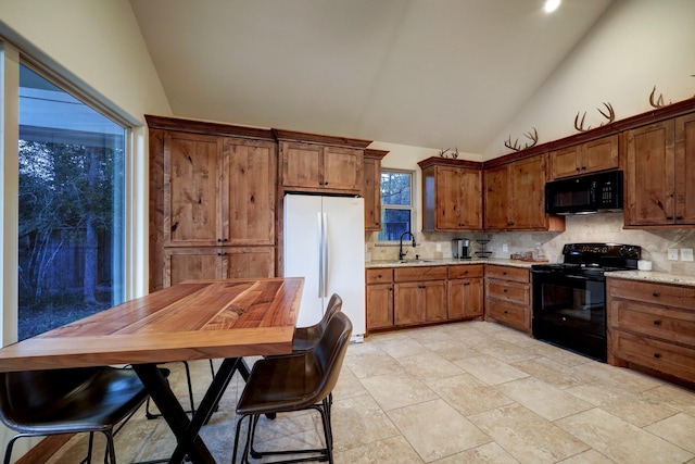 kitchen featuring lofted ceiling, sink, tasteful backsplash, light stone countertops, and black appliances