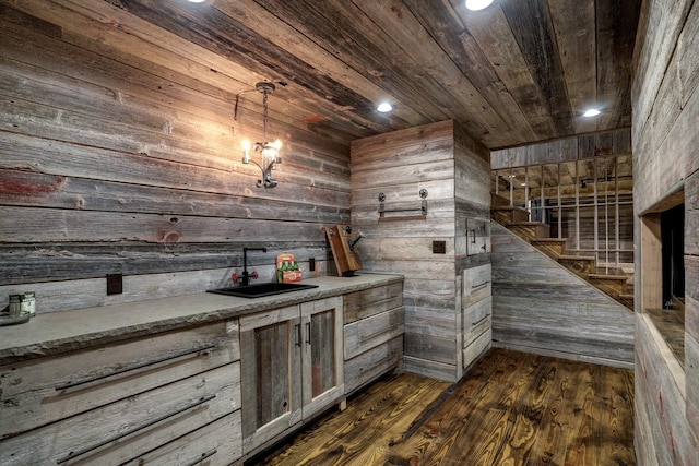 bar featuring dark hardwood / wood-style floors, wooden walls, decorative light fixtures, sink, and wooden ceiling