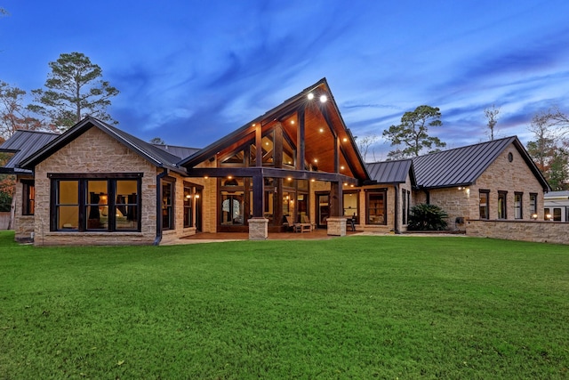 back house at dusk with a patio and a yard